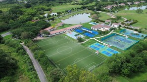 Eine Vogelperspektive eines Golfplatzes mit Tennisplatz, Schwimmbad und einem großen Teich.