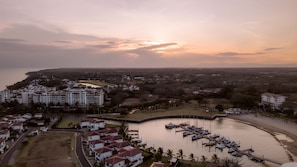 A coastal residential area with a marina, buildings, and a hilly landscape in the background.