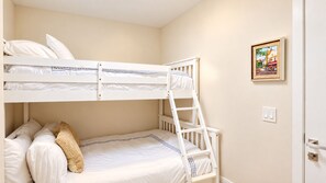 Ein Schlafzimmer mit Etagenbett, einer Leiter, einem gerahmten Bild an der Wand und einer Tür mit Lichtschalter.