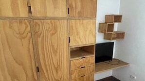 Ein Schlafzimmer mit einem Holzkasten, einem Bett und einem Fernseher auf einer Holzablage.