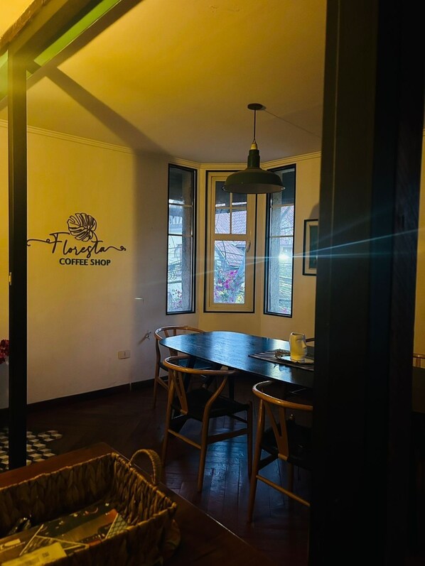 A cozy coffee shop interior with a wooden table, chairs, and a hanging light fixture.