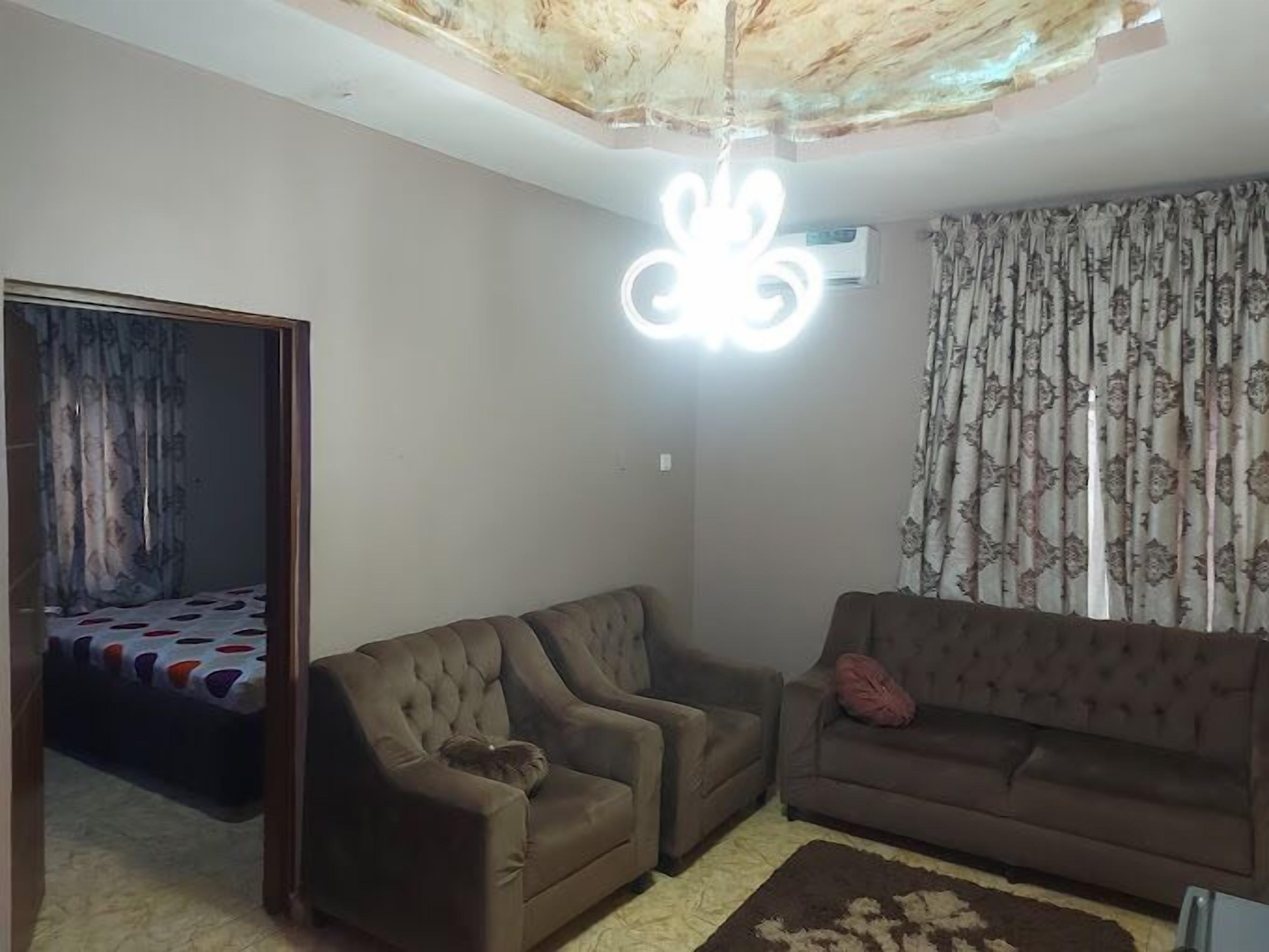 Un salon avec un canapé, un fauteuil et un rideau à motifs.