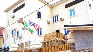 A two-story building with a balcony and a decorative gate. - Hotel Dopepi (Abuja)