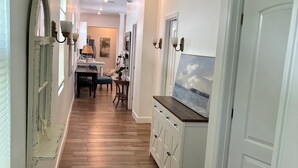 Un pasillo con piso de madera, paredes blancas y un área de comedor con una mesa y sillas.