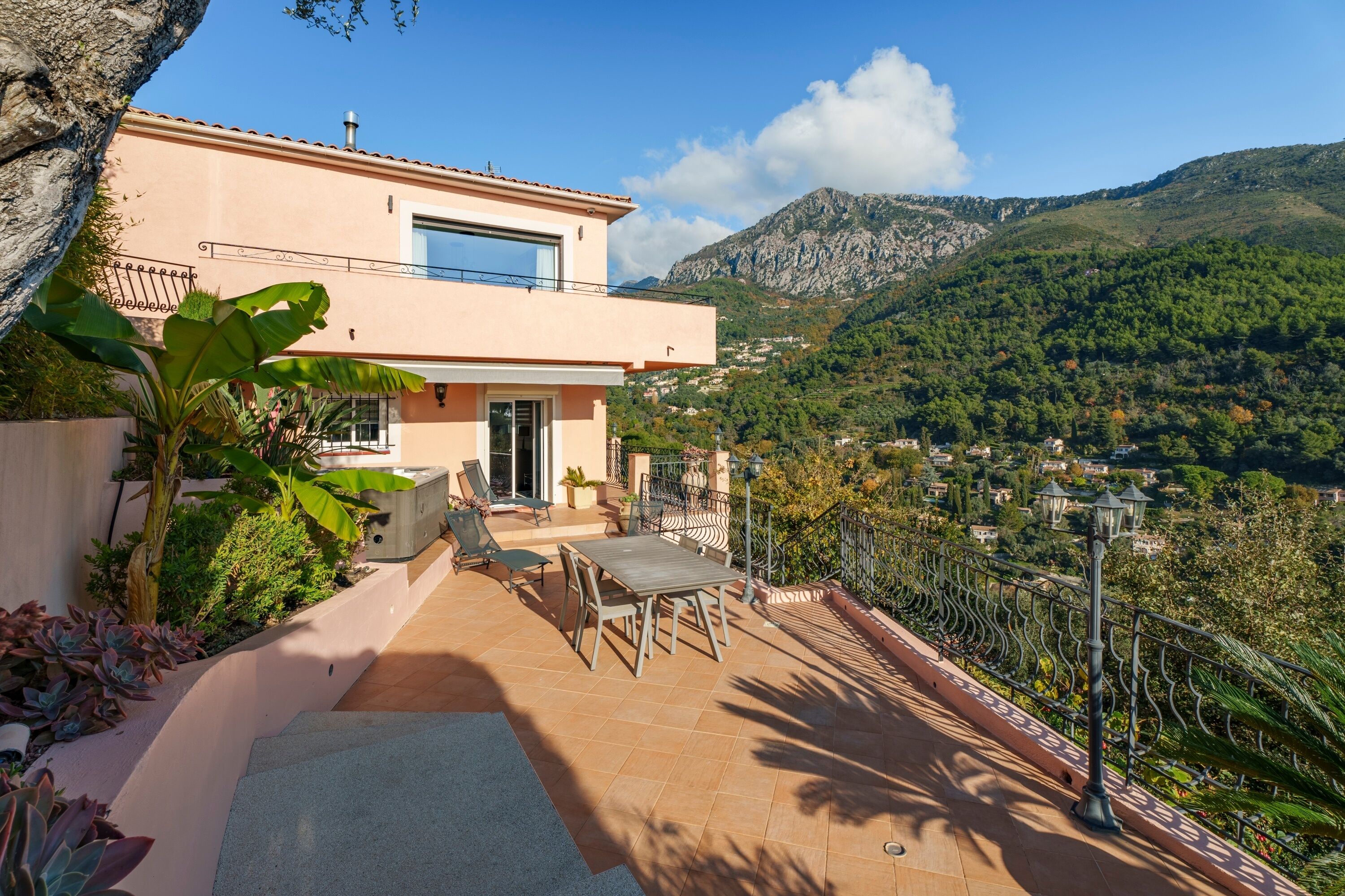 Una casa moderna con patio, mobili da esterno e vista su un paesaggio montuoso.