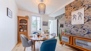Un coin repas avec une table ronde, des chaises bleues, un meuble en bois et un mur orné de motifs.