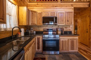 Una cocina con armarios de madera, electrodomésticos de acero inoxidable y encimera negra.