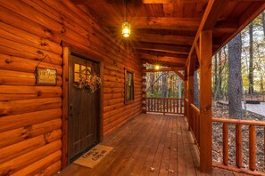 A wooden cabin with a porch, a welcome sign, and a door with a doormat.