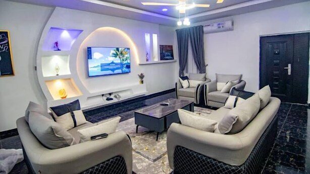 Un salon moderne doté d’un téléviseur à écran plat, de sièges confortables et d’un plafond décoratif.