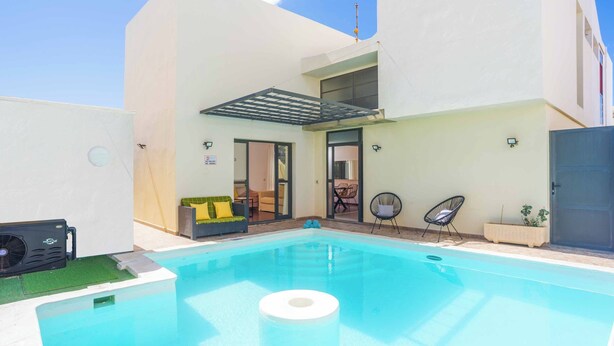 A modern outdoor pool area with a clear blue pool, a covered seating area, and a small patio with outdoor furniture. - Villa Lanzabur - Three Bedroom Villa, Sleeps 6 (Teguise)