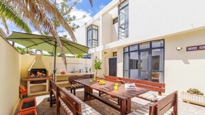 A patio with a wooden table and benches, a grill, and a potted plant. - Villa Lanzabur - Three Bedroom Villa, Sleeps 6 (Teguise)