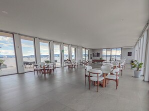 A spacious indoor area with multiple seating arrangements, large windows, and a view of the outside.