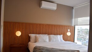 Ein Hotelzimmer mit einem großen Bett, einem Holzkopfbrett, zwei Nachttischlampen und einer Klimaanlage.