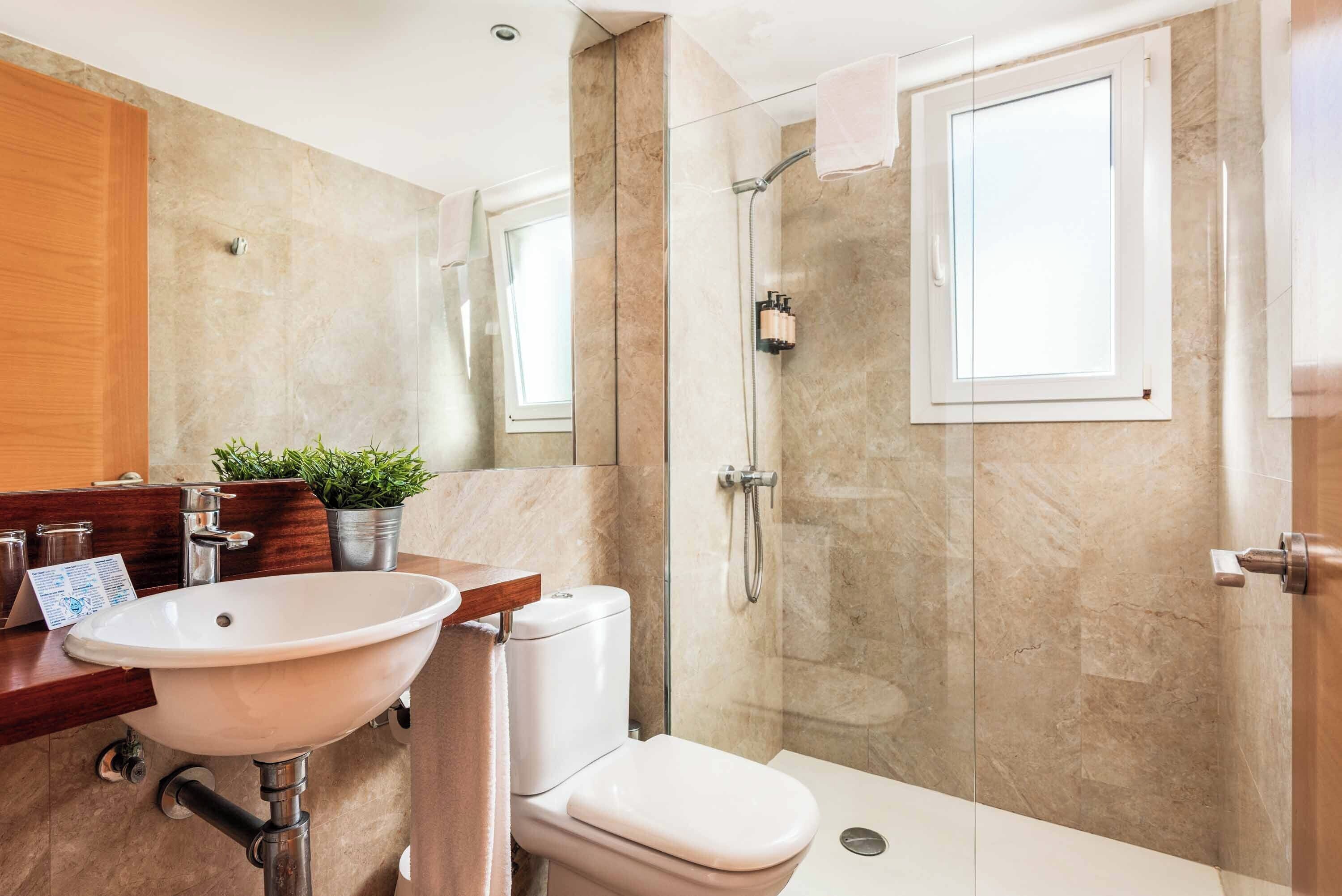 Un baño moderno con lavamanos, inodoro y ducha.