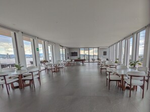 Une salle de conférence spacieuse offrant une vue panoramique sur la ville, équipée de mobilier moderne et d’un téléviseur à écran plat.