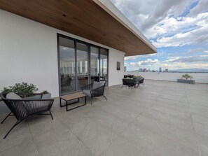 Une terrasse sur le toit, aménagée avec des sièges, offrant une vue sur le panorama urbain et dotée d’un plafond en bois.