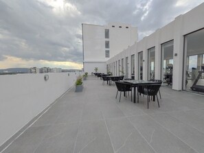 Une terrasse sur le toit, dotée de sièges extérieurs, avec un bâtiment moderne en arrière-plan.