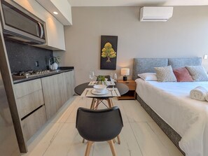 Une chambre d’hôtel moderne équipée d’un lit, d’une table de chevet et d’un coin repas avec une table et des chaises.