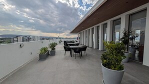 Eine Dachterrasse mit Essbereich, Topfpflanzen und Blick auf die Stadt.
