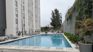 Ein rechteckiger Swimmingpool mit Liegestühlen und einer Topfpflanze.