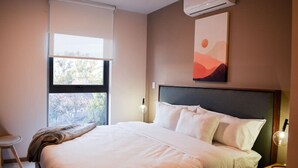 A bedroom with a bed, a window, a painting, and a nightstand with a lamp. - New Loft near Andares B (Zapopan)