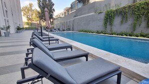 Un espace aménagé au bord de la piscine, avec des chaises longues et une piscine.