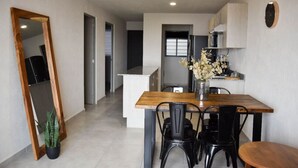 Eine moderne Küche mit Holztisch und -stühlen, einem Kühlschrank und einer Vase mit Blumen.