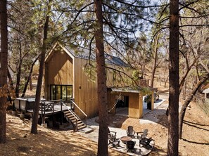 Una cabaña con fachada de madera, una terraza y mobiliario exterior.
