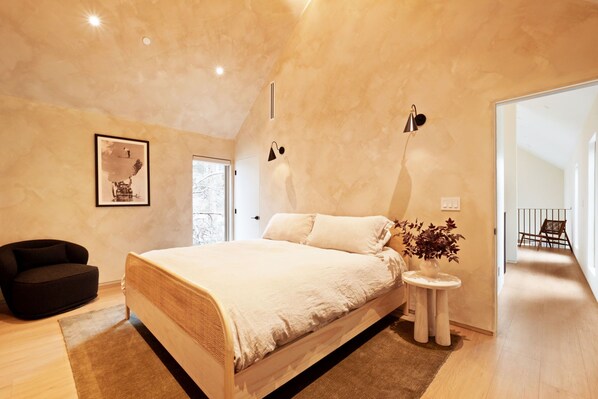 Un dormitorio moderno con una cama grande, una mesita de noche con una planta y un cuadro en la pared.
