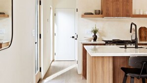 A modern kitchen with a central island, wooden cabinets, and a black pendant light.
