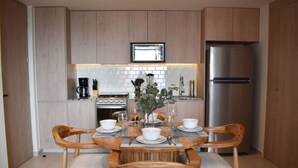 A modern kitchen with wooden cabinets, a stainless steel refrigerator, and a dining table set for four with chairs. - New apartment with incredible view in YU Country 1804 (Guadalajara)
