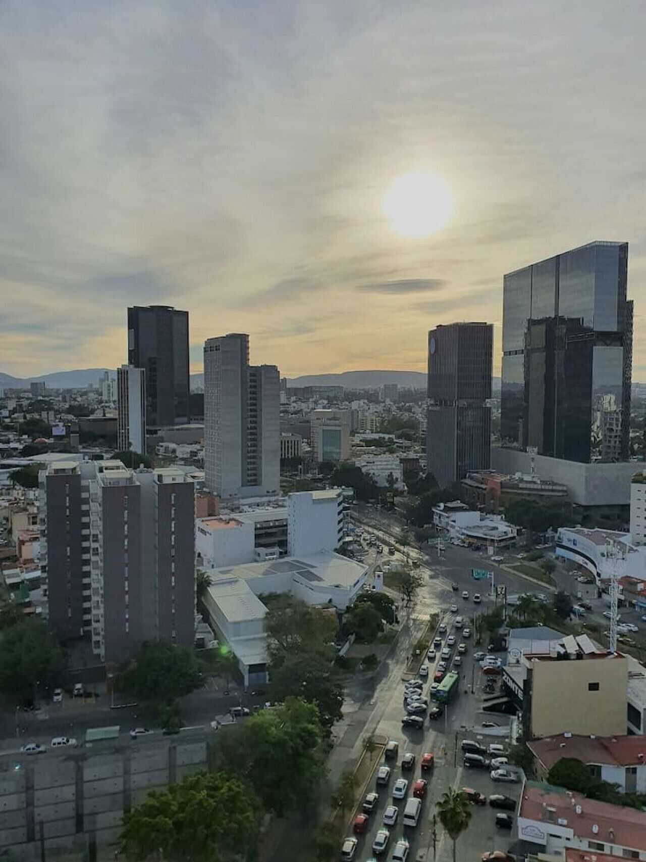 A cityscape with modern high-rise buildings, a busy street with cars, and a clear sky.