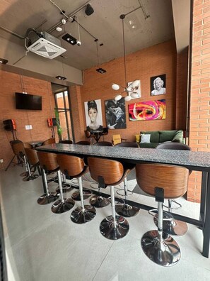 A modern bar area with a long counter, wooden bar stools, and a TV mounted on the wall. - New Loft with incredible view in YU Country 1507B (Guadalajara)