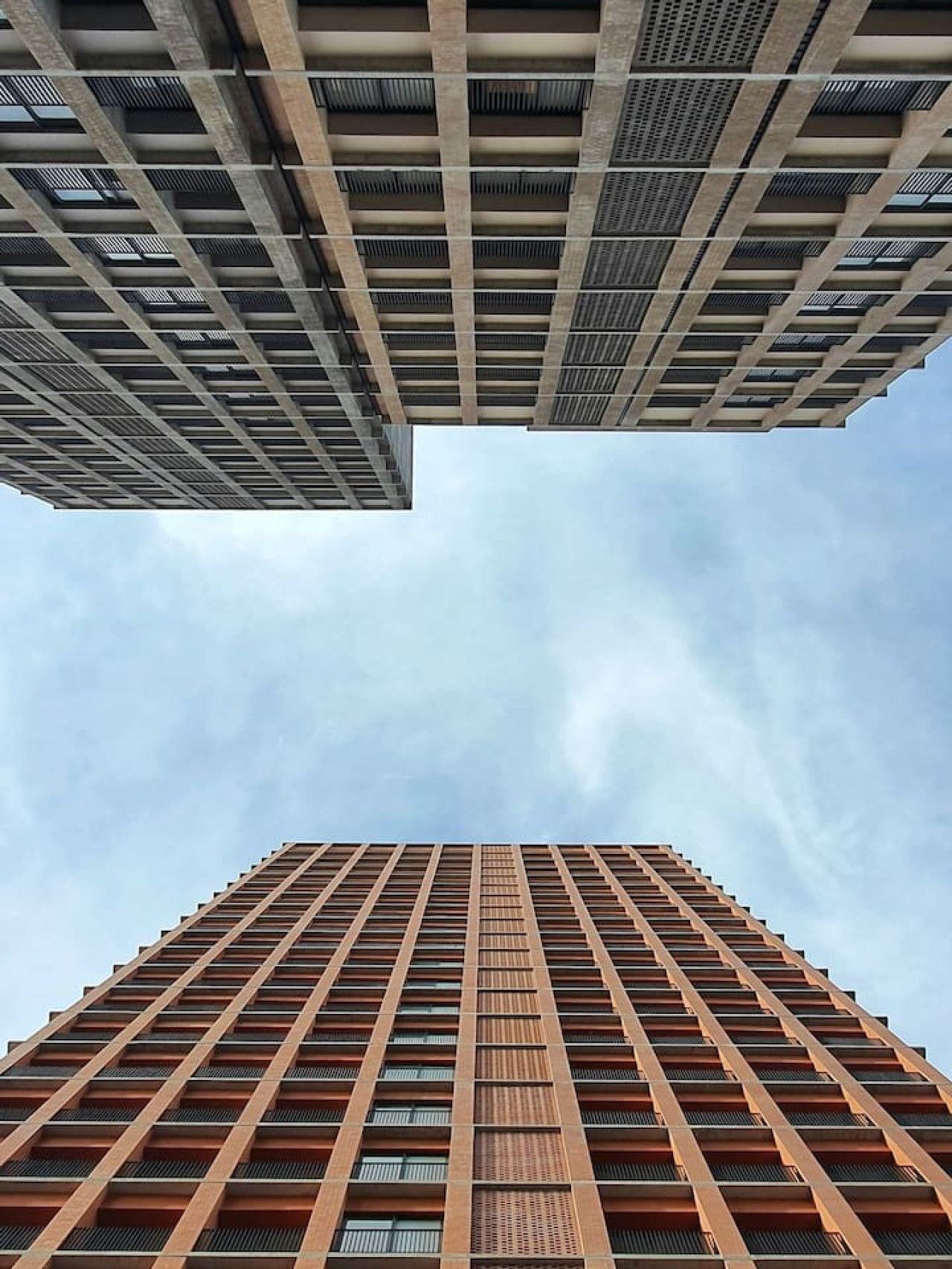 Een hoog gebouw met een gevel van rasterwerk en veel ramen.