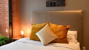 Une chambre moderne avec un grand lit, une tête de lit et un tableau représentant un paysage de montagne.