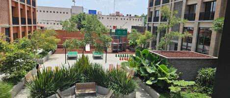 Un área de patio al aire libre con asientos y macetas, rodeada de edificios.