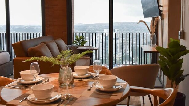 A dining area with a table set for two, a sofa, and a TV mounted on the wall. - 24th floor with the best view of Guadalajara (Guadalajara)