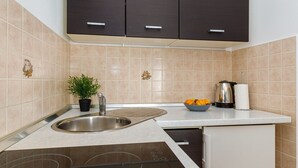 A modern kitchen with dark cabinets, a stainless steel sink, a built-in dishwasher, and a kettle on the counter. - Beachfront Escape in Rovinj - Sea Studio (Rovinj)