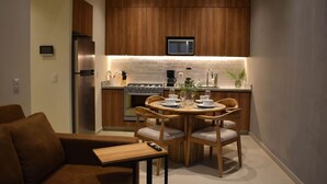 A modern kitchen with wooden cabinets, a built-in microwave, a gas stove, and a dining area with a round table and chairs. - New Penthouse with the best view of GDL 2503B (Guadalajara)