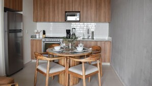 A modern kitchen with wooden cabinets, a built-in microwave, a stove, and a dining area with a round table and chairs. - New Penthouse with the best view of GDL 2503B (Guadalajara)