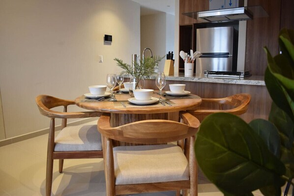 Un comedor con una mesa redonda de madera, cuatro sillas y una planta en maceta.