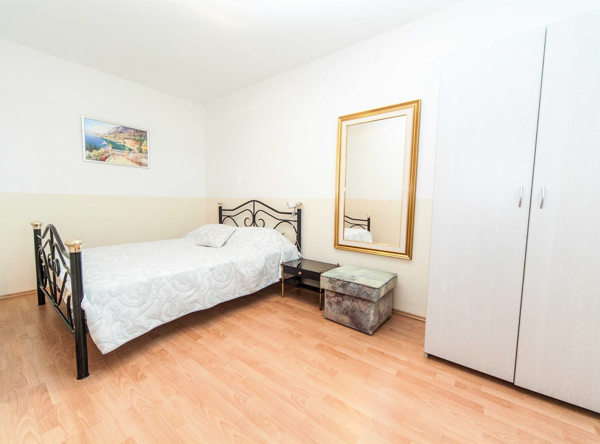 Een slaapkamer met een bed, nachtkastje, kledingkast en een schilderij aan de muur.