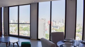 Habitación de hotel moderna con ventanas amplias que ofrecen vistas a la ciudad.