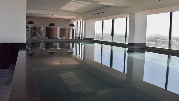 Una amplia piscina interior con grandes ventanales que ofrecen vistas a la ciudad.