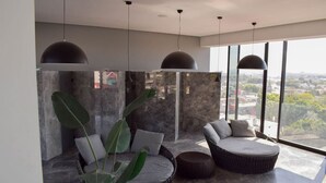 Una sala de estar moderna con un ventanal grande, un rincón de estar circular y una planta grande.