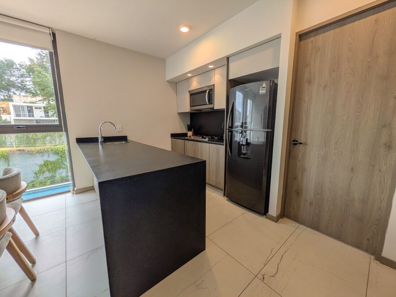 Una cocina moderna con una isla central, electrodomésticos de acero inoxidable y vistas a un patio.