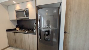 A modern kitchen with a stainless steel refrigerator, a built-in microwave, and a coffee maker.