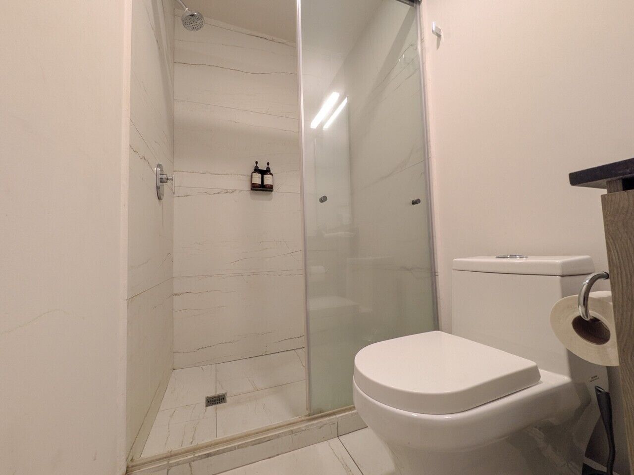 A bathroom with a glass-enclosed shower, a toilet, and a sink.