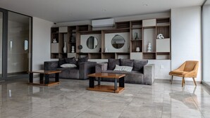 Een moderne woonkamer met een zithoek, twee bijzettafels en een fauteuil.