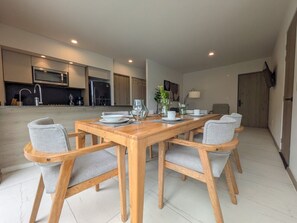 A modern kitchen with a dining area featuring a wooden table and grey upholstered chairs. - Amazing new apartment near Andares 310A (Zapopan)